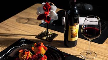 A dining table with a plate of food, a wine bottle, and a wine glass.