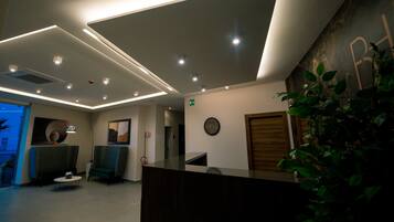 A modern reception area with a reception desk, seating, and a wall-mounted clock.