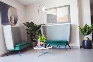 A modern living room with a green sofa, a small round coffee table, and a potted plant. - Building Hotel (Carinaro)