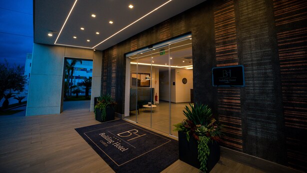 A modern hotel entrance with a glass door, a reception desk, and a sign indicating the hotel name. - Building Hotel (Carinaro)
