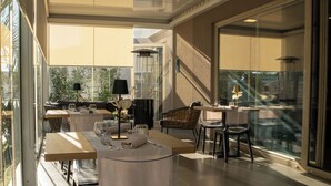 A dining area with tables set for two, a large window with a view, and a modern interior design. - Building Hotel (Carinaro)