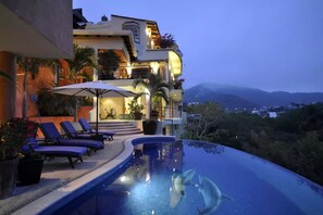 A poolside area with lounge chairs and a view of a mountainous landscape.