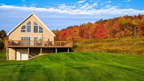A two-story house with a balcony, a garage, and a well-maintained lawn. - Hilltop Country Home with Panoramic Views – Peaceful and Private Retreat (Walton)