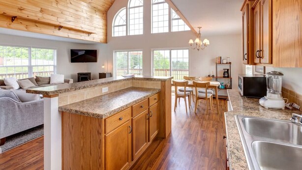 A spacious kitchen with wooden cabinets, a granite countertop, and a dining area with a table and chairs. - Hilltop Country Home with Panoramic Views – Peaceful and Private Retreat (Walton)