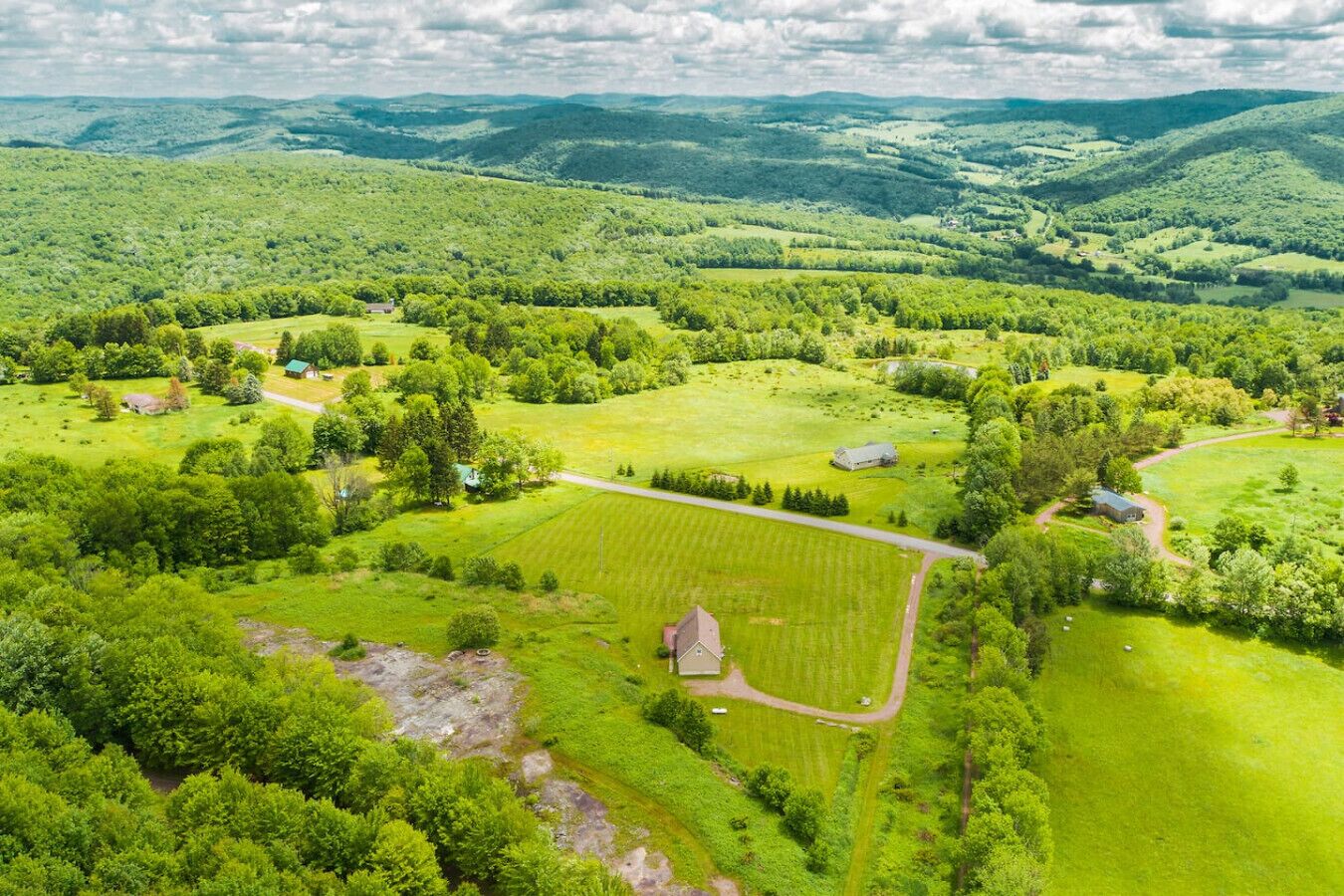 An aerial view of a rural landscape with fields, trees, and scattered buildings.