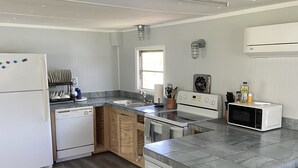 Une cuisine moderne dotée d’un îlot central, d’appareils électroménagers intégrés et d’une fenêtre laissant entrer la lumière naturelle.