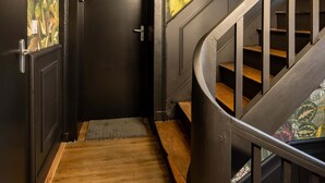 A staircase with a wooden handrail and a dark wall. - Studio B, in the city center, cozy and warm... (La Roche-sur-Yon)