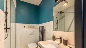 A modern bathroom with a glass shower enclosure, a white toilet, and a vanity with a mirror. - Studio B, in the city center, cozy and warm... (La Roche-sur-Yon)