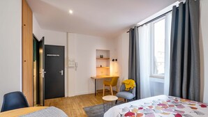 A modern hotel room with a bed, a desk, a chair, and a small table. - Studio B, in the city center, cozy and warm... (La Roche-sur-Yon)