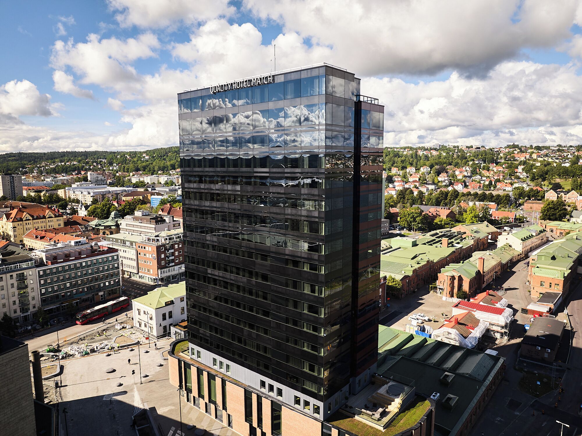 Et moderne hotel med en glasfacade, flere etager og udsigt over byens skyline.