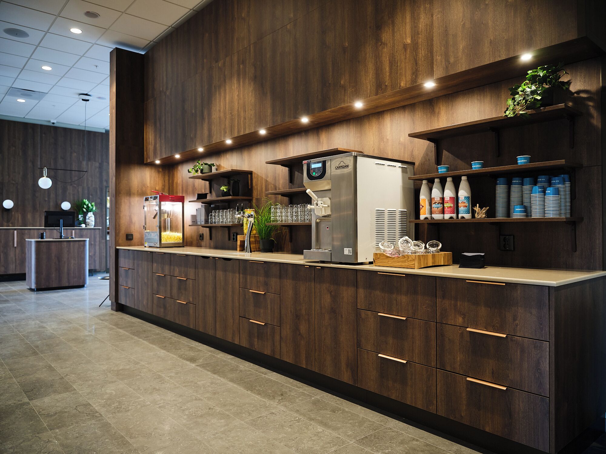 Zona de bar moderna con una máquina de café, cristalería y dispensadores de bebidas.