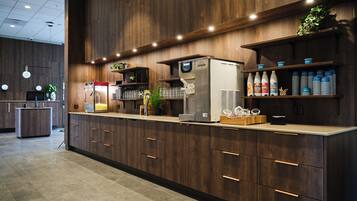 A modern bar area with a coffee machine, glassware, and beverage dispensers.