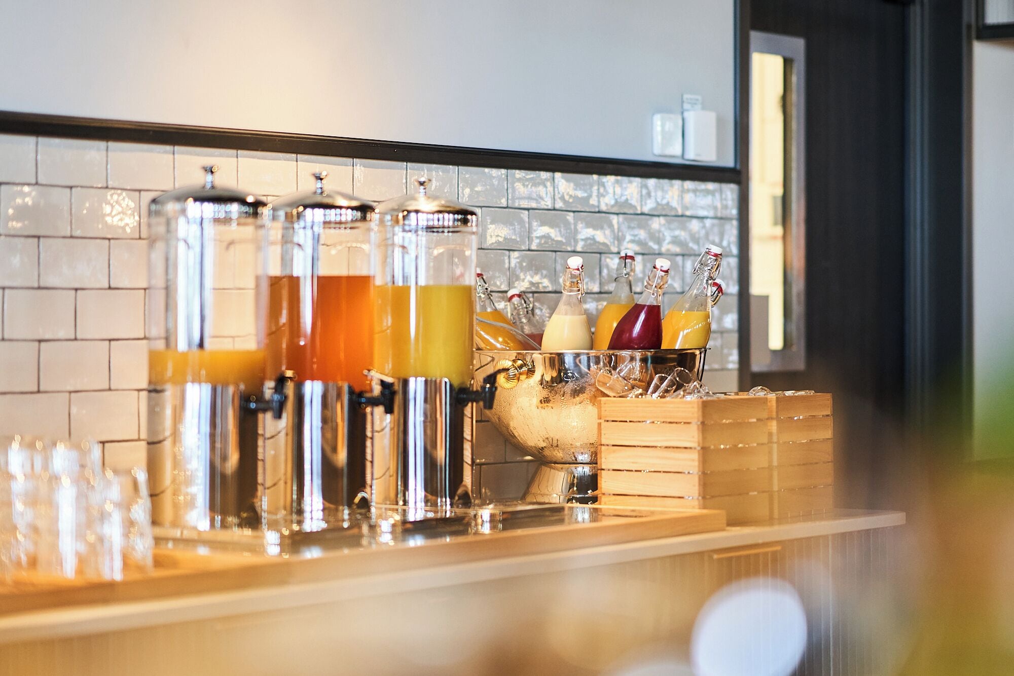Una zona de bar con varios dispensadores de bebidas y un bol grande de fruta.
