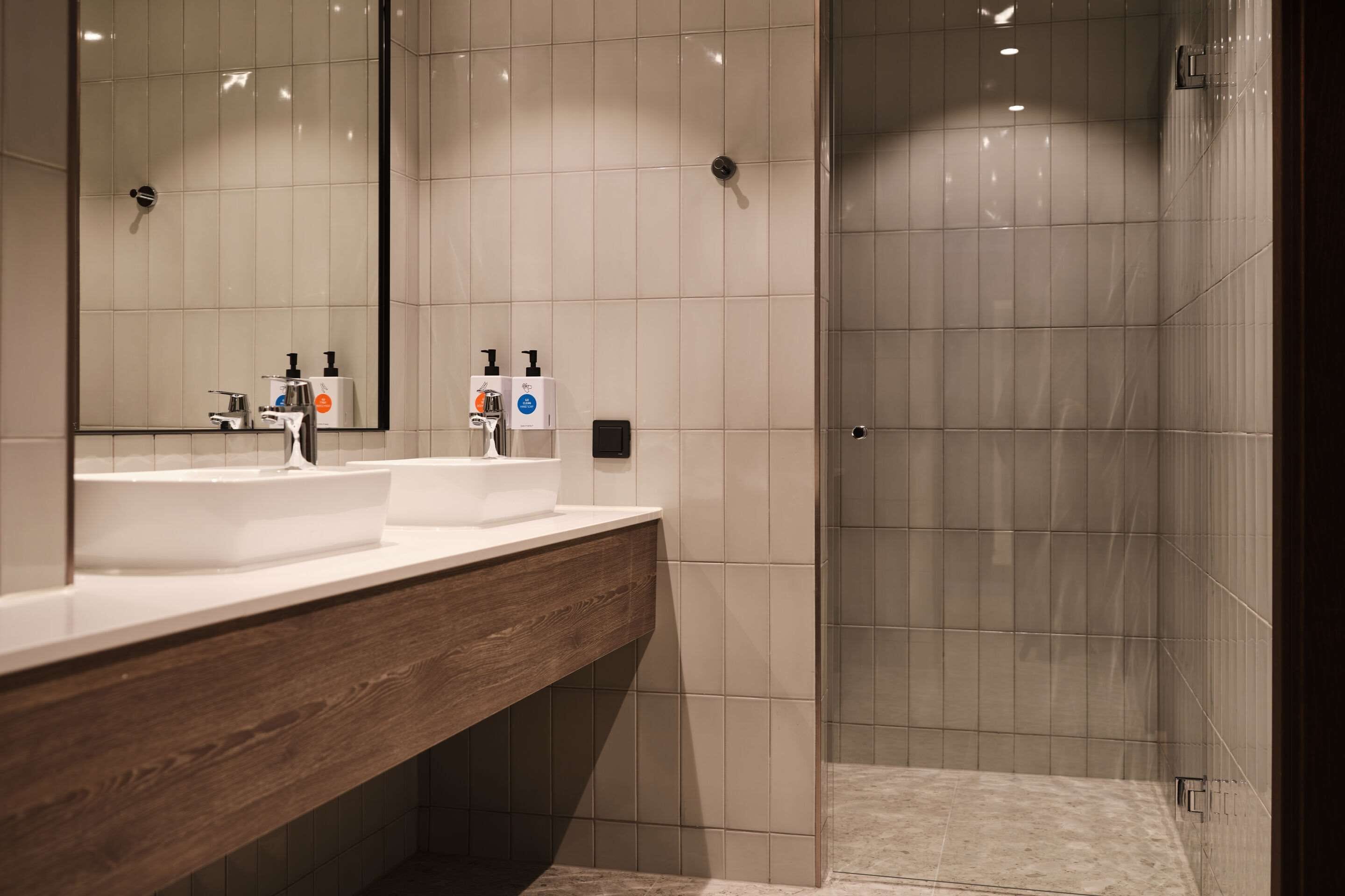 Une salle de bain moderne avec un meuble-lavabo en bois, un grand miroir et un espace douche.