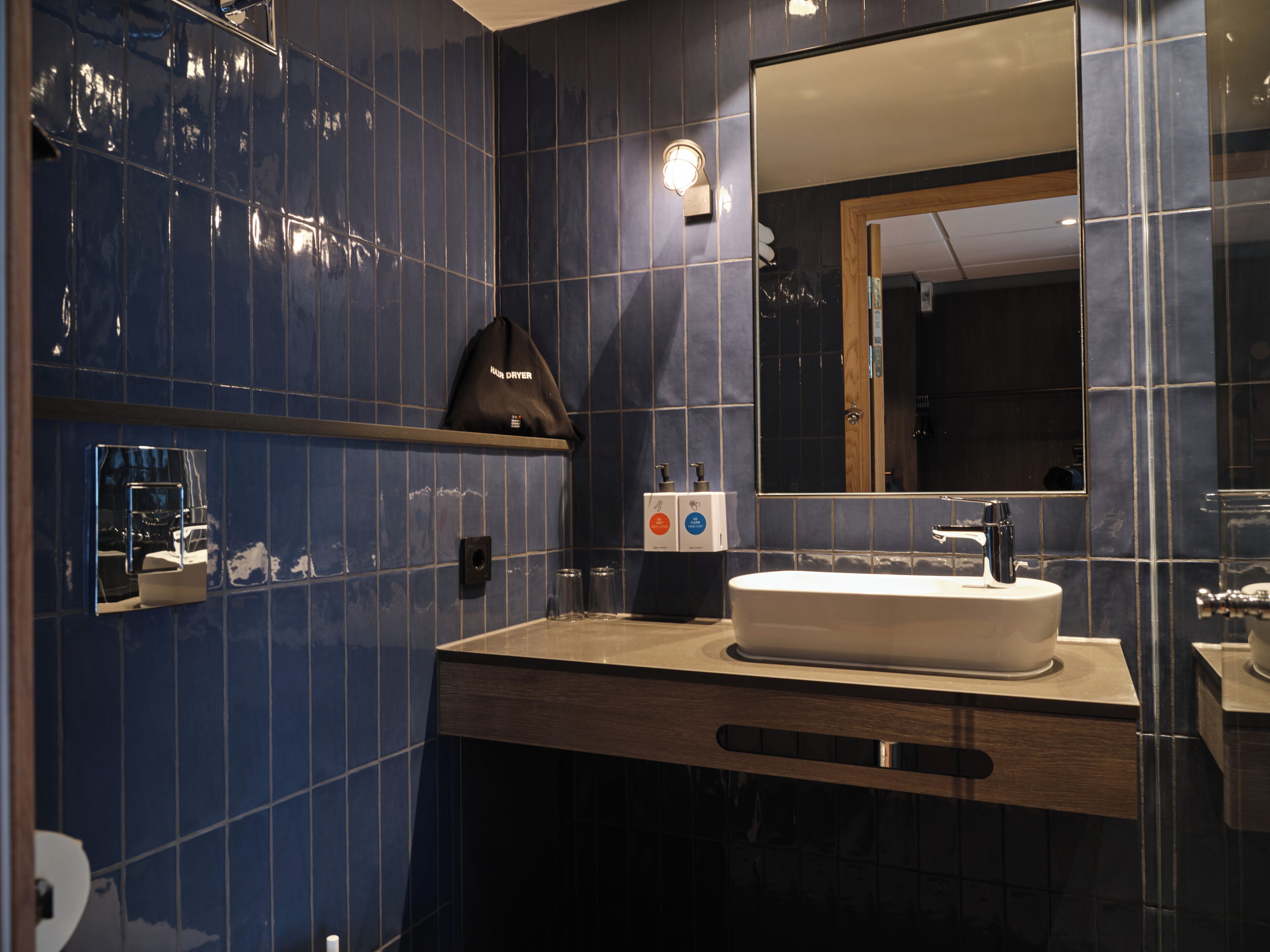 Un baño moderno con un espejo grande, un lavabo blanco y un perchero para toallas.