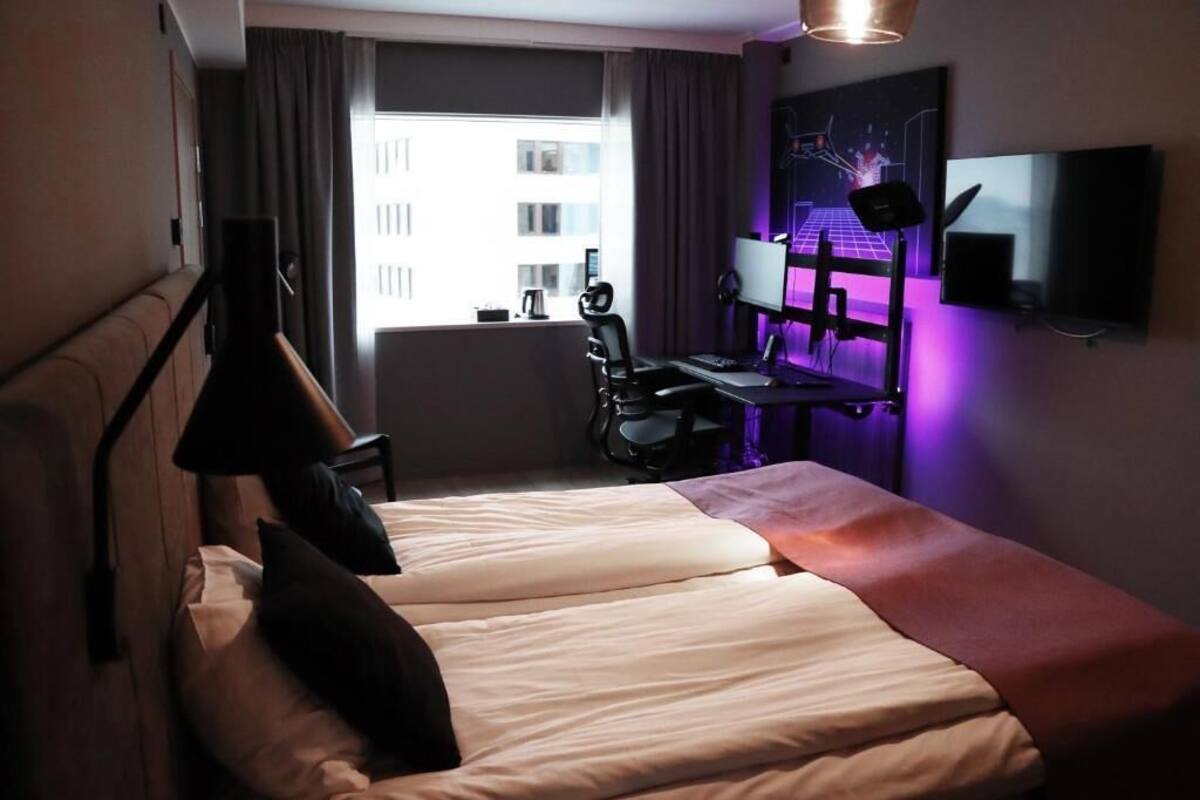 Une chambre d’hôtel avec un lit, un bureau avec un ordinateur, une chaise et un téléviseur.
