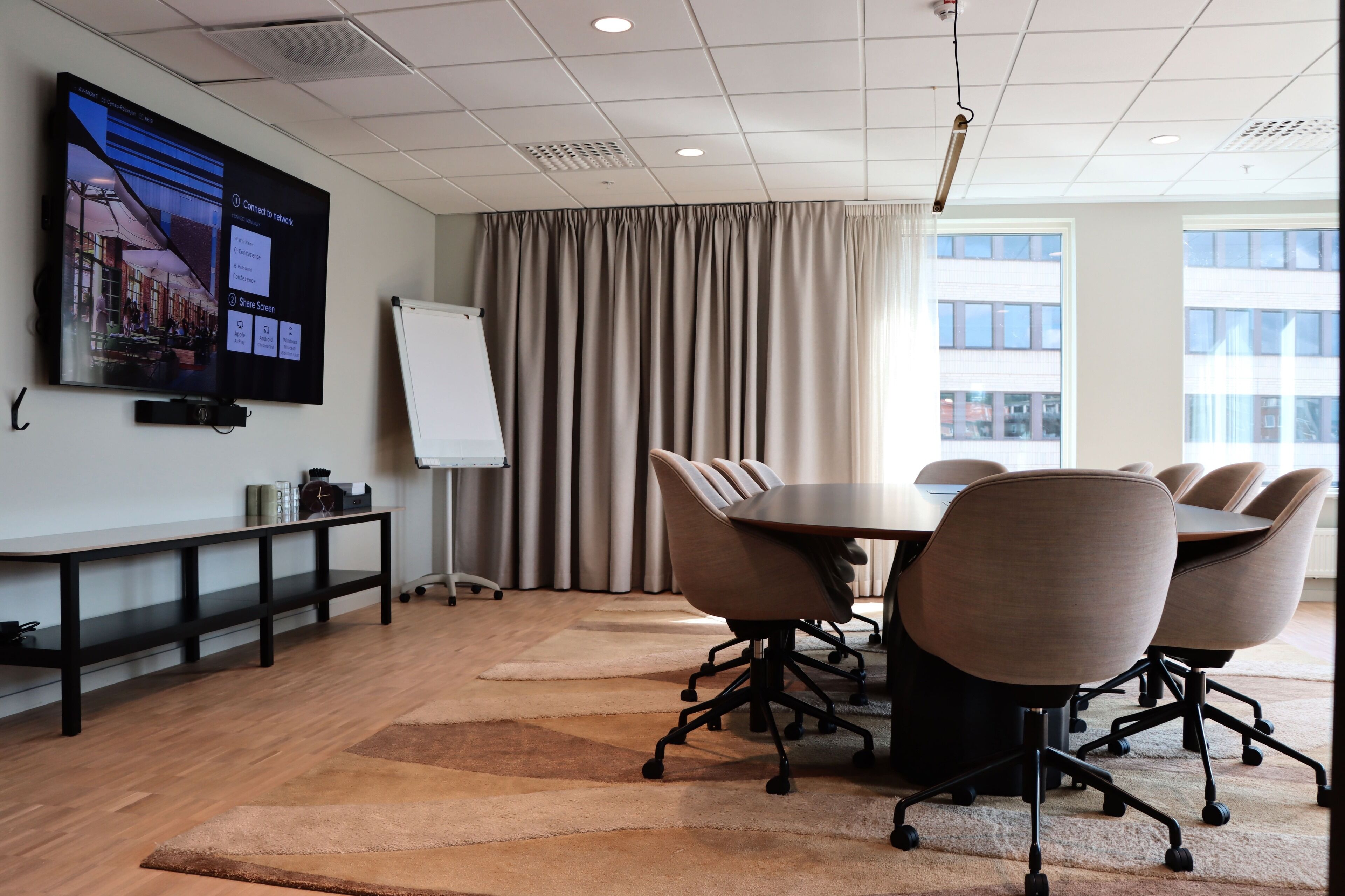 A conference room with a large screen, a whiteboard, and a round table with chairs.