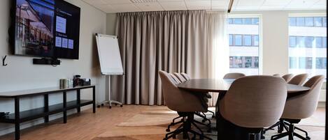 A conference room with a large screen, a whiteboard, and a round table with chairs.