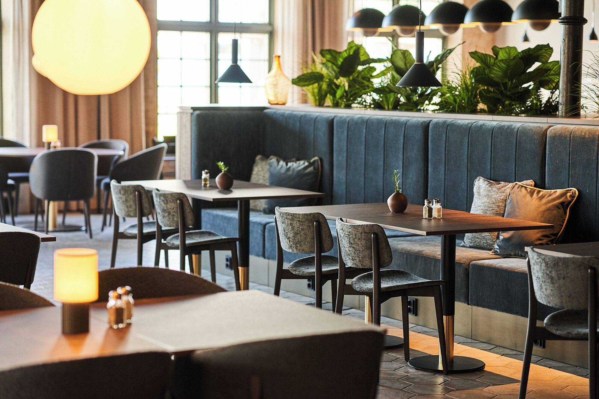 A modern restaurant with a cozy seating area featuring a sofa and multiple tables.