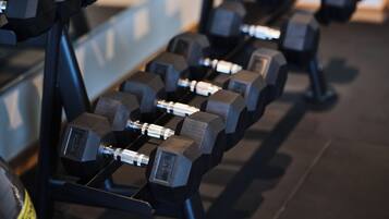 A rack of black dumbbells in a gym.