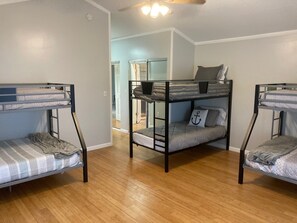 Une pièce avec trois lits superposés, un plancher en bois et un luminaire au plafond.