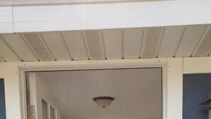 Uma porta dá entrada a um quarto com uma janela redonda, uma escrivaninha e uma cadeira.