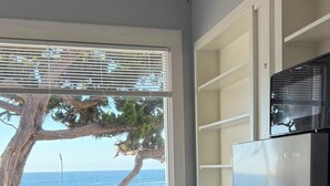 Una cocina moderna con un refrigerador de acero inoxidable, una mesa de comedor con sillas y vistas al mar a través de grandes ventanales.