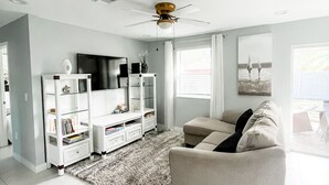 Ein modernes Wohnzimmer mit einem weißen Sofa, einer Glasvitrine und einem Deckenventilator.