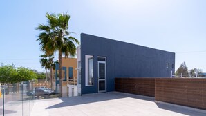 Ein modernes Gebäude mit blauer Fassade, einem Glastür-Eingang und einer gefliesten Terrasse.