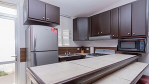 Eine kleine Küche mit Kühlschrank, Mikrowelle, Herd und Holzschränken.