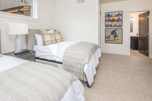 A hotel room with two beds, a nightstand, a lamp, and artwork on the wall.