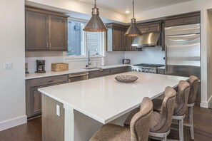 A modern kitchen with dark wood cabinets, stainless steel appliances, and a central island with bar stools.
