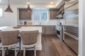 A modern kitchen with dark wood cabinets, stainless steel appliances, and a large island with bar stools.