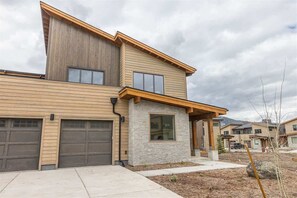 A modern two-story house with a garage, stone facade, and a sloped roof.