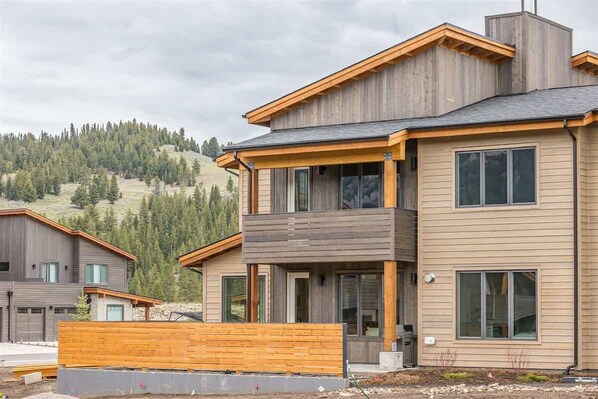 A modern two-story house with a wooden facade, large windows, and a balcony.