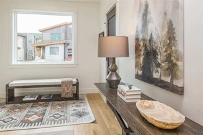 A modern interior with a bench, a lamp, a rug, and a painting of trees.