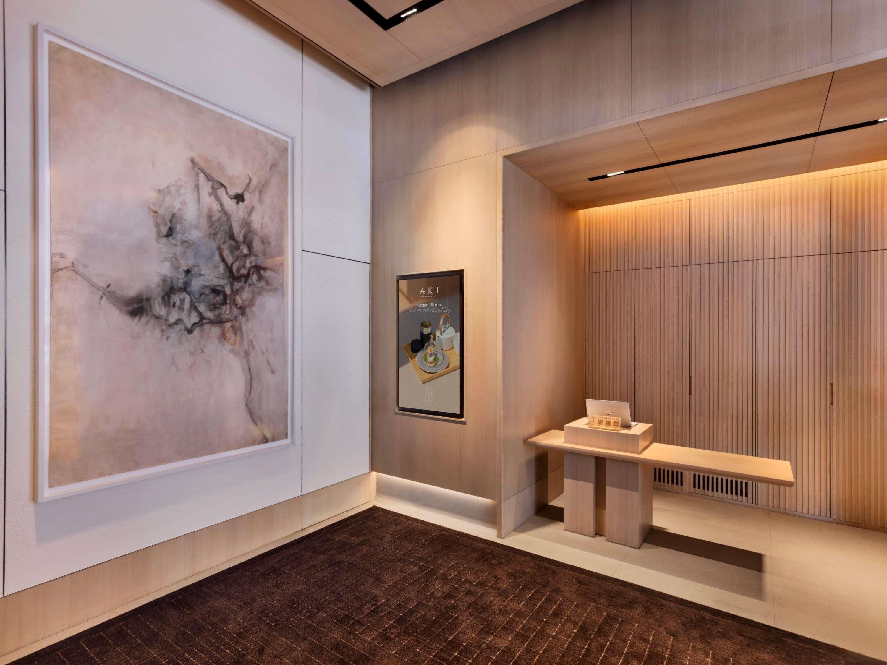 A modern lobby with a large abstract painting, a framed menu, and a reception desk.
