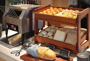 A bakery display with various breads and pastries, a toaster oven, and a sign indicating the type of bread available. - AKI Hotel Hong Kong - MGallery Collection (Hong Kong)