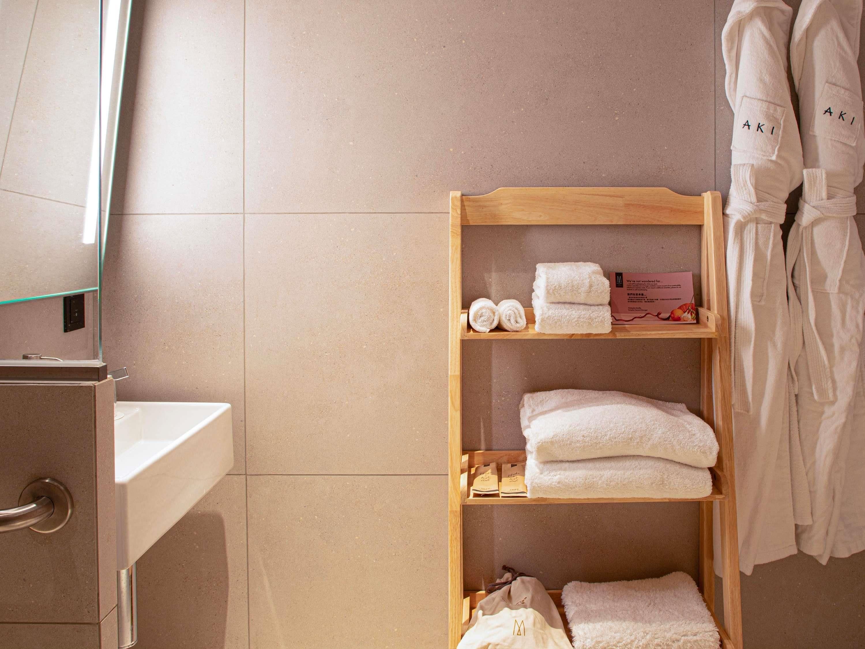 A bathroom with a wooden shelf holding towels and toiletries.