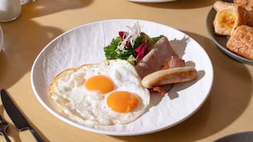 A breakfast plate with eggs, bacon, and a side salad.
