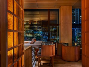 Een bar met uitzicht op de stad, houten meubels en een groot raam.