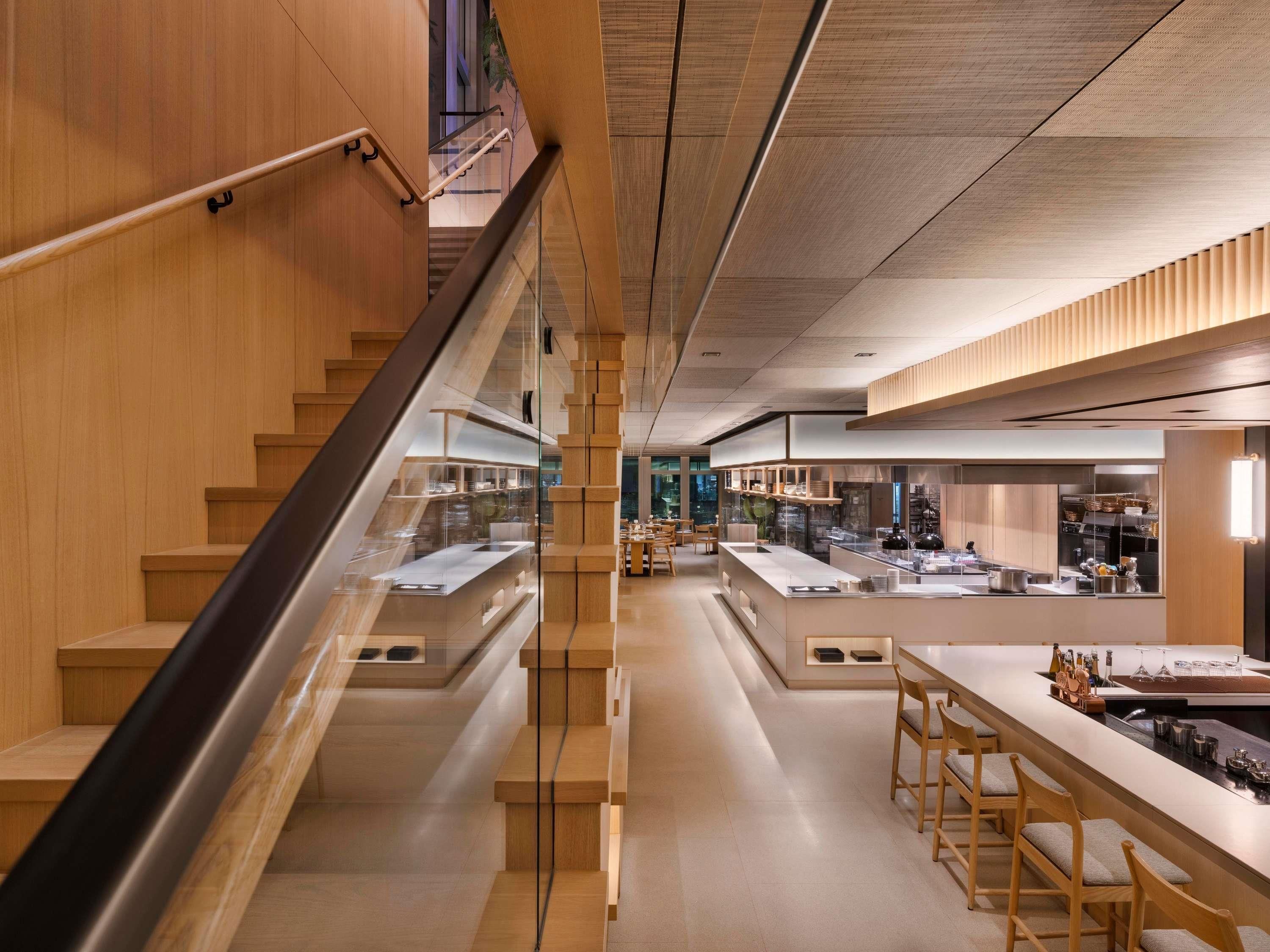 A modern interior with wooden accents, a central staircase, and a bar area with stools and a counter.