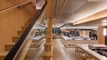 A modern interior with wooden accents, a central staircase, and a bar area with stools and a counter.
