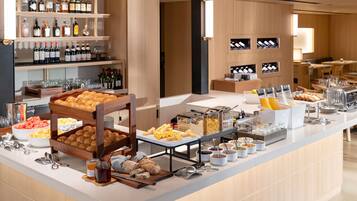 A buffet with various food items, a wine selection, and a seating area.