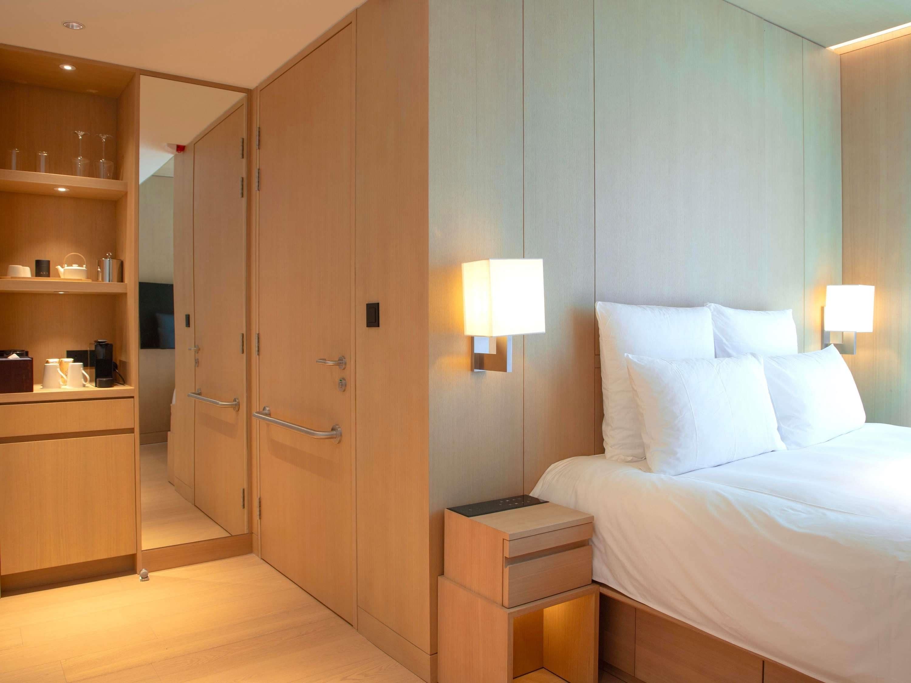 Une chambre d’hôtel comprenant un lit, des tables de chevet, une armoire et un miroir.