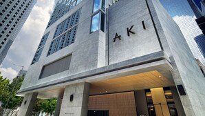 A modern building with a prominent 'AKI' sign, featuring a glass facade and a concrete base. - AKI Hotel Hong Kong - MGallery Collection (Hong Kong)