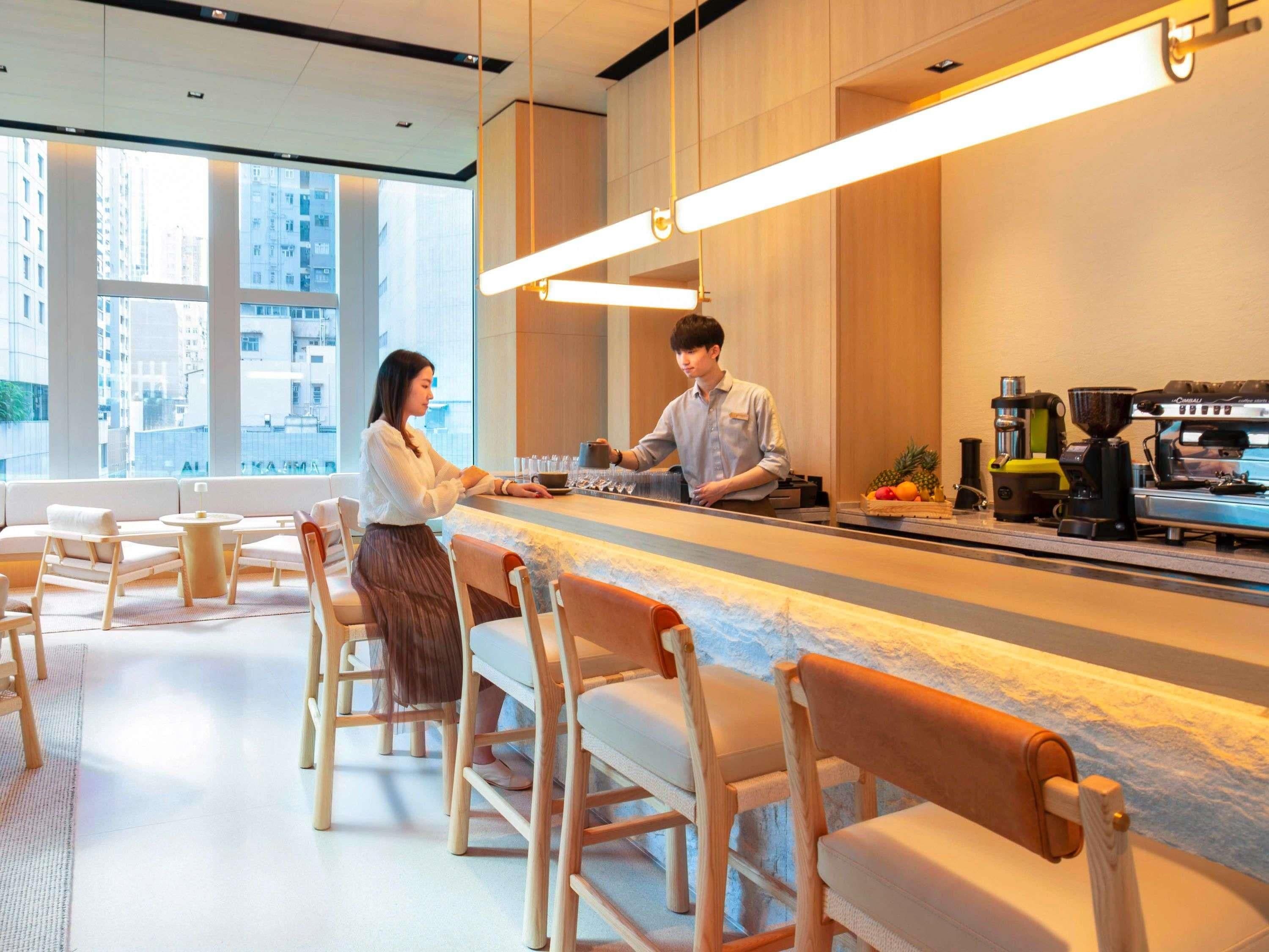 Un café moderne avec un long comptoir, des tabourets de bar et une machine à café.