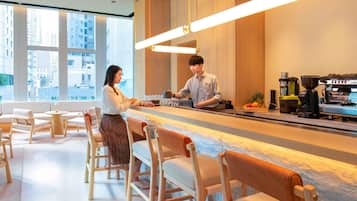 Un café moderne avec un long comptoir, des tabourets de bar et une machine à café.
