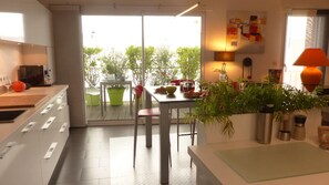 Een moderne keuken met een eetgedeelte, een schuifdeur naar een balkon en uitzicht op groen.