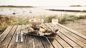 A wooden table with a plate of oysters, a glass of white wine, and a basket of bread. - Vannes, 4-star luxury flat with car park (Vannes)